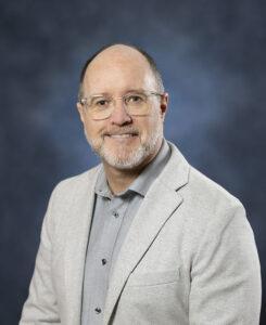 Gentleman in grey suit and glasses promoting mental health and wellness.