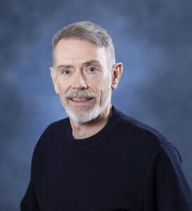 Experienced man with grey hair and beard, smiling for health and wellness photography.