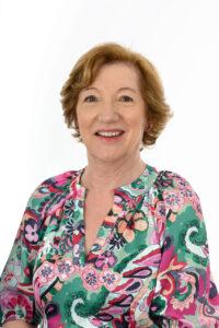Relaxed woman smiling, health and wellness, nature and holistic therapy, smiling lady, vibrant floral top, calm and balanced lifestyle.