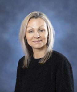Relaxed woman with blonde hair smiling, healthcare professional at Mind & Body Works.