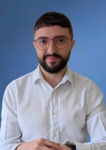 Calm man with beard and glasses in a white shirt.