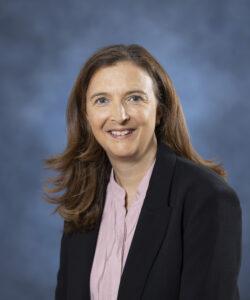 Professional woman in business attire for health and wellness coaching.