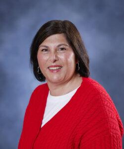 Relaxed woman smiling in red cardigan for holistic wellness.