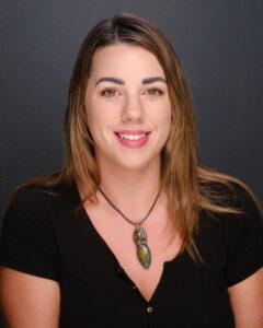 Bright smiling woman with brown hair and a colourful pendant necklace, Holistic therapist, Mind & Body Works, wellness and relaxation expert, professional therapy session, mental health care, alternative medicine, holistic healing, body and mind therapy, mental wellbeing, Tavistock, Devon.