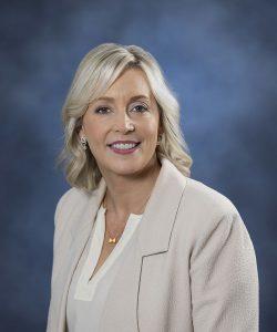 Professional woman with blonde hair smiling in a business portrait.