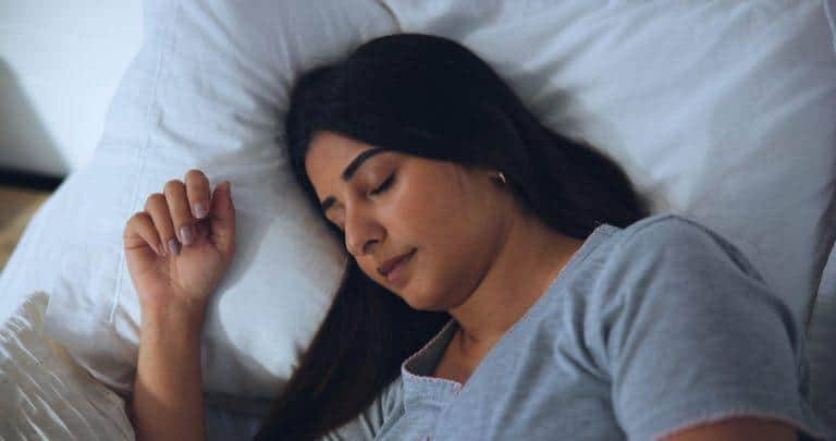 Relaxing woman sleeping peacefully in bed for stress relief and well-being.