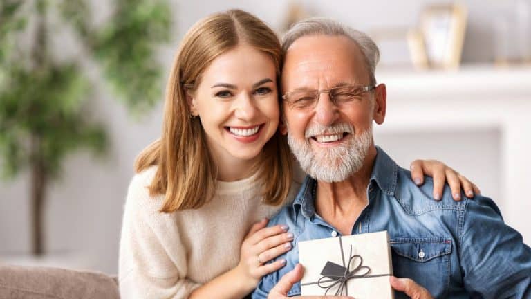 Father and daughter smiling together, holding a gift, showing strong bond.