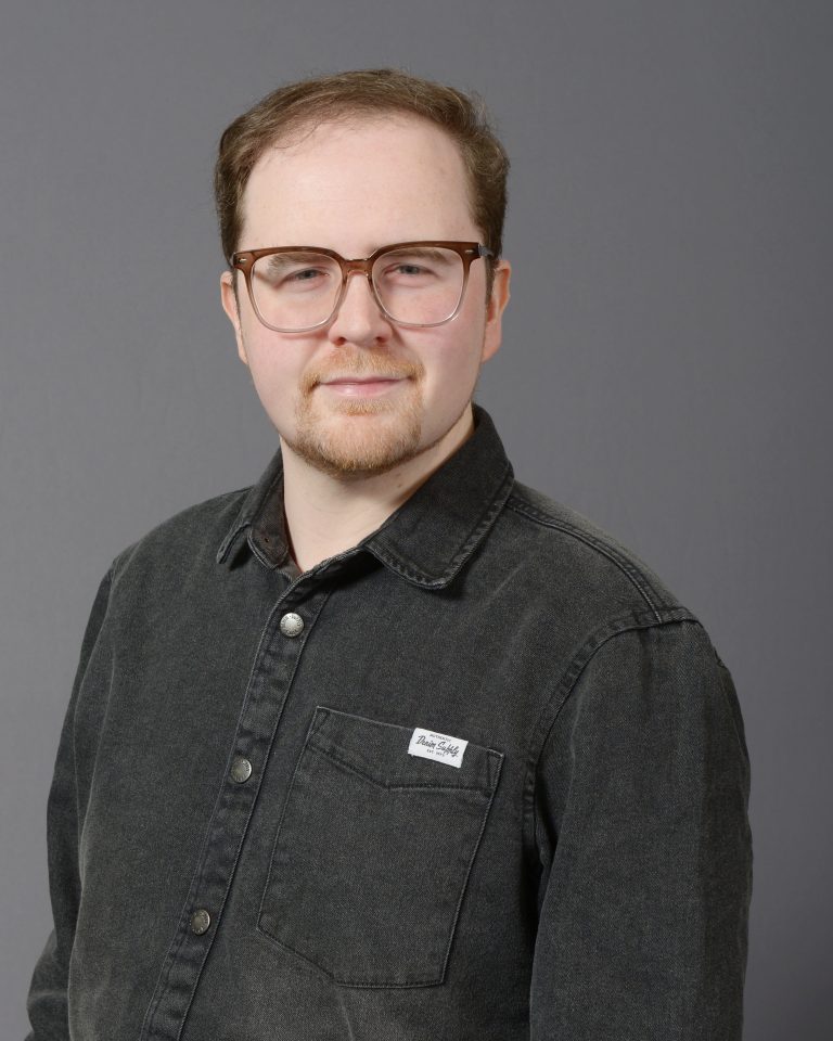 Professional man in glasses and black shirt at Mind & Body Works.