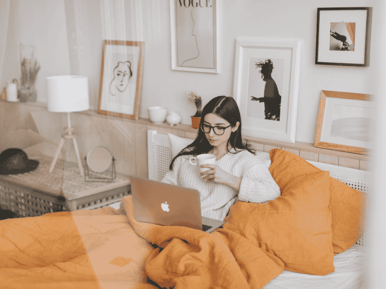 Online therapy session with a woman using a laptop in a cozy bedroom.