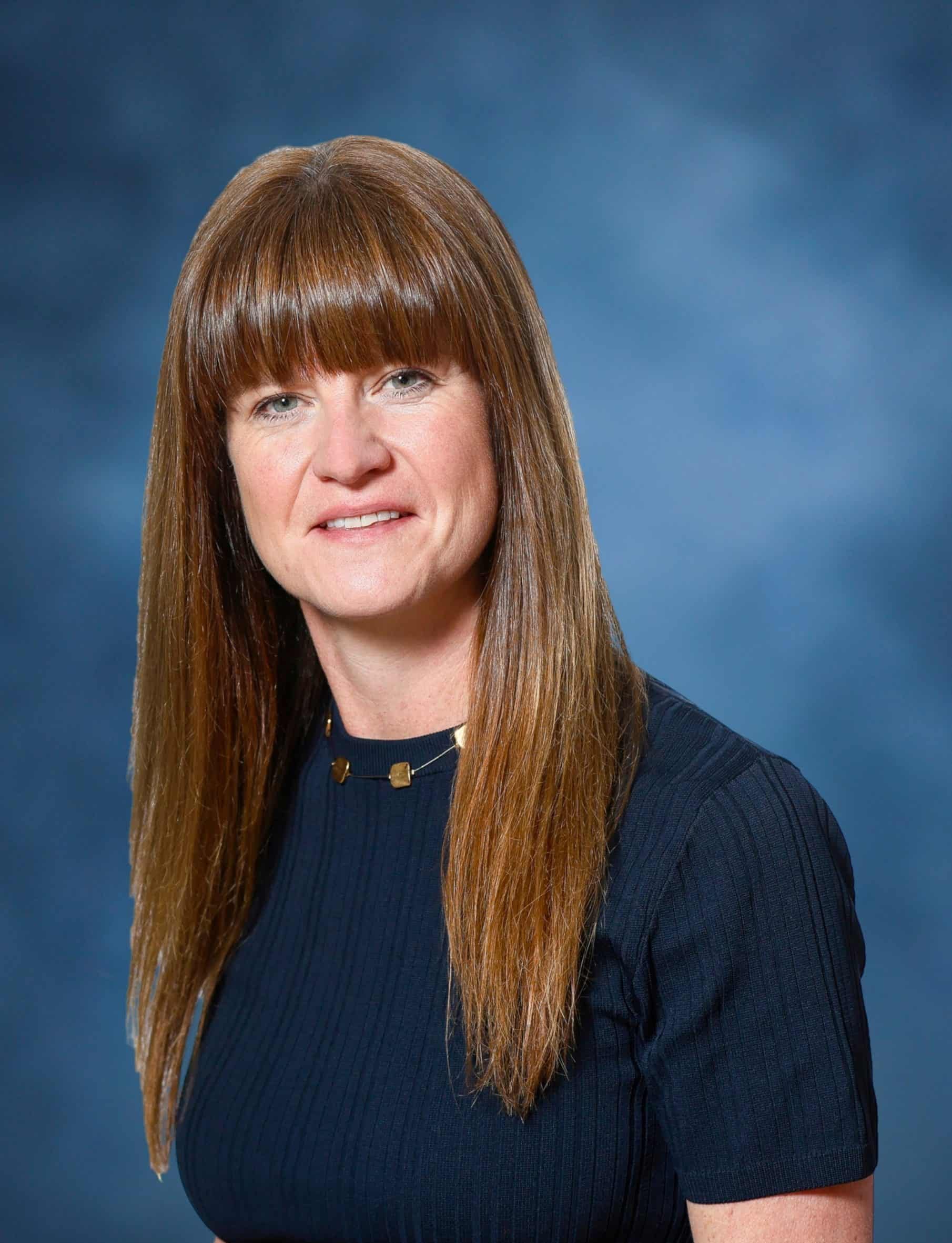 Confident woman with long red hair in a professional setting at Mind & Body Works.