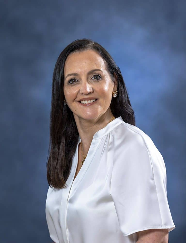 Relaxed woman in white blouse smiling, health and wellness professional portrait.