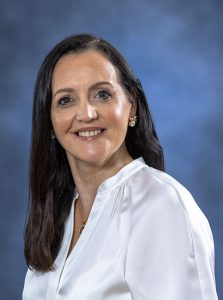 Relaxed woman in white blouse smiling, health and wellness professional portrait.