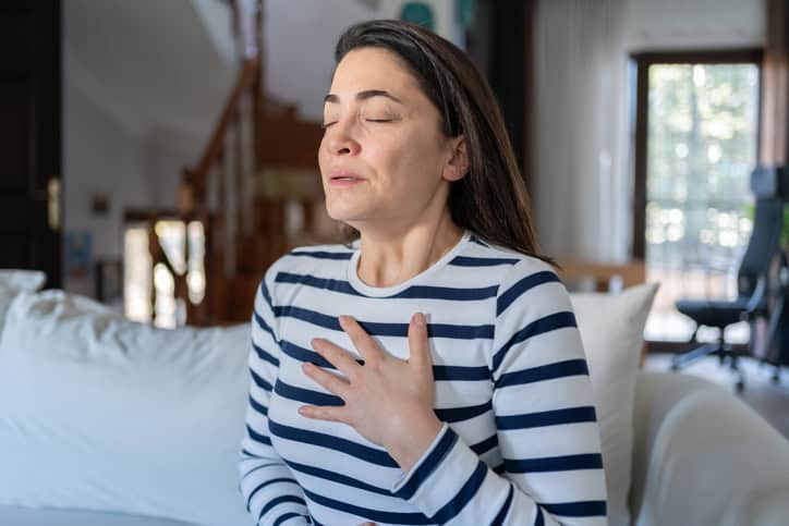 Relaxed woman experiencing chest discomfort at home, health and wellness concept.
