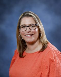 Relaxed woman with glasses smiling, professional headshot for wellness and therapy services.