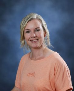 Smiling woman in peach T-shirt against blue background for Mind & Body Works.