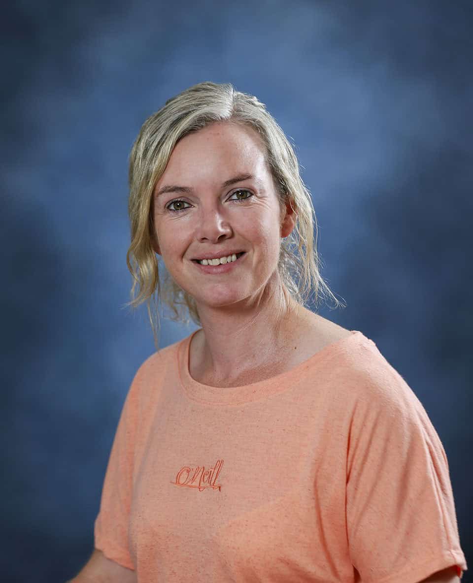 Smiling woman in peach T-shirt against blue background for Mind & Body Works.