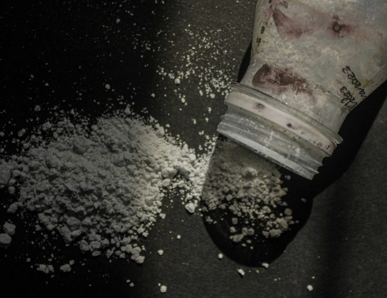 Spilled cocaine on a dark surface with a tube of the drug nearby.