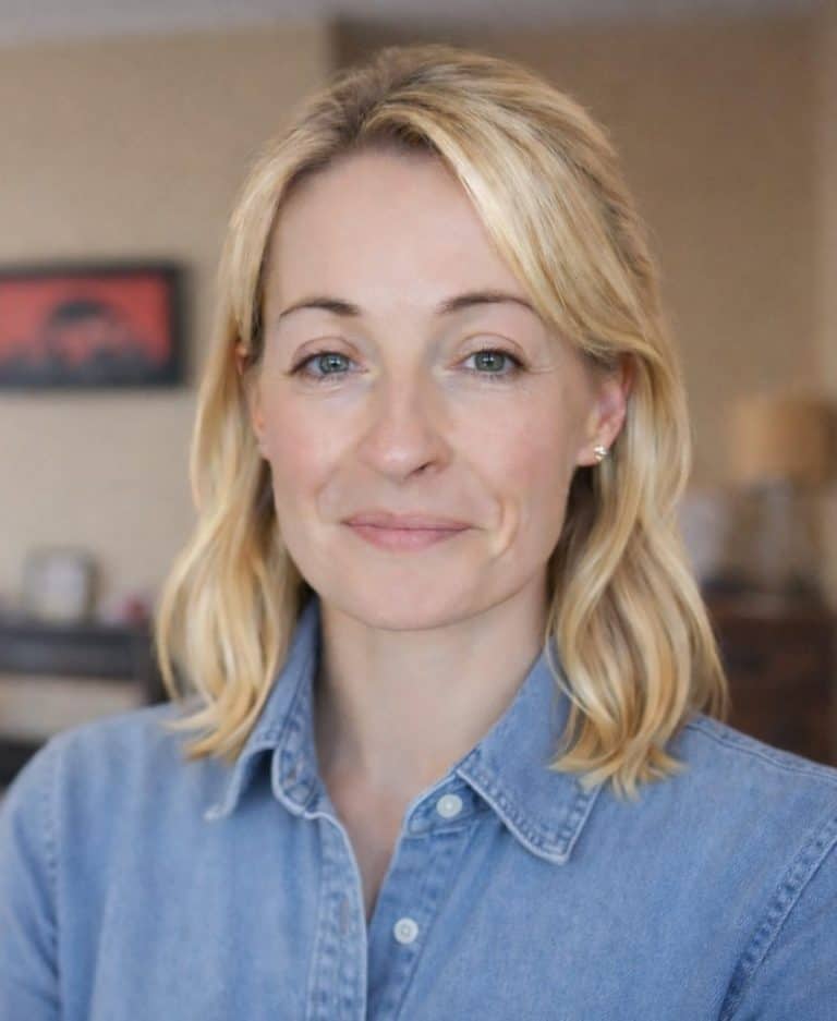 Professional woman with blonde hair in a casual denim shirt smiling at the camera.
