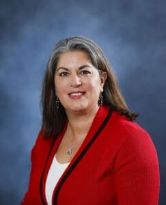 Professional woman in red blazer smiling for health and wellness photo.